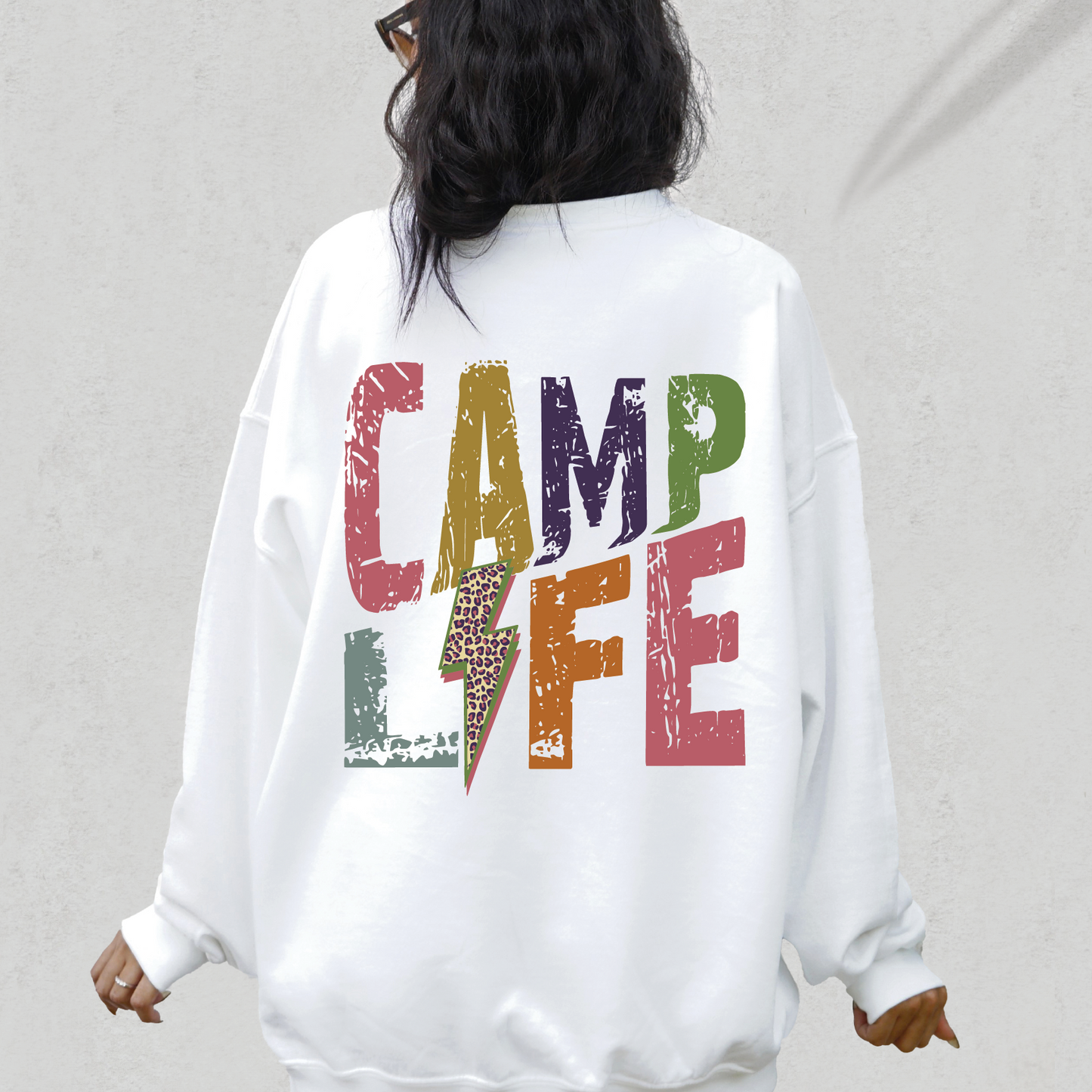 a woman wearing a white sweatshirt with the words camp life printed on it