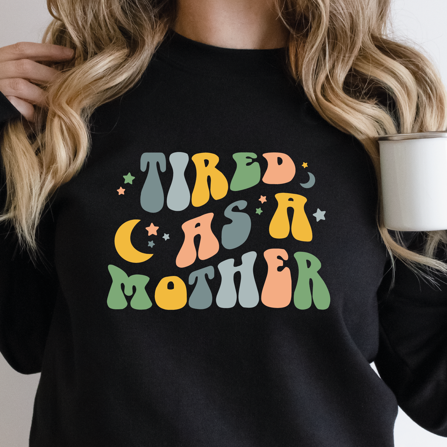 a woman is holding a coffee mug and wearing a black sweatshirt with the words tired