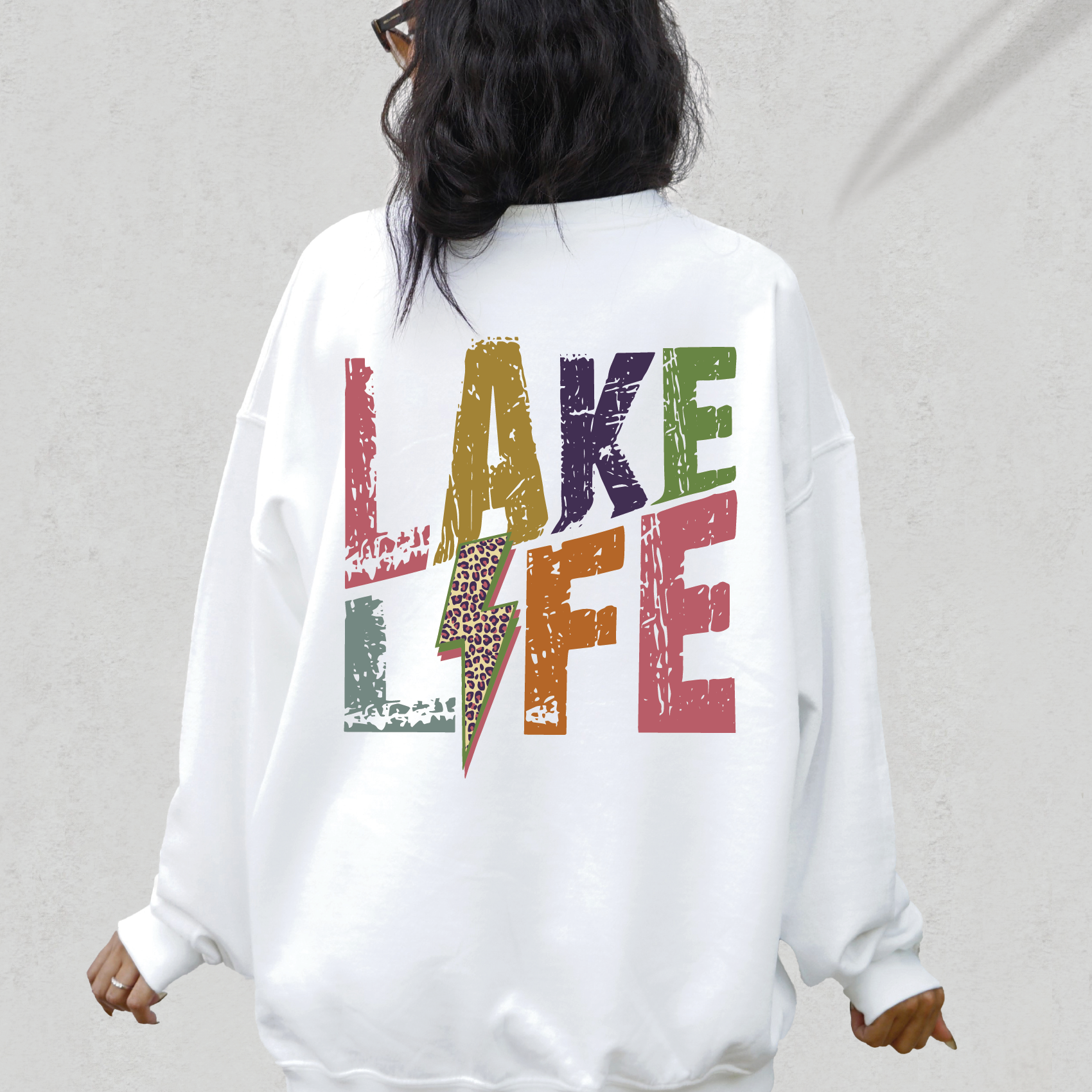 a woman wearing a white sweatshirt with the words lake life printed on it